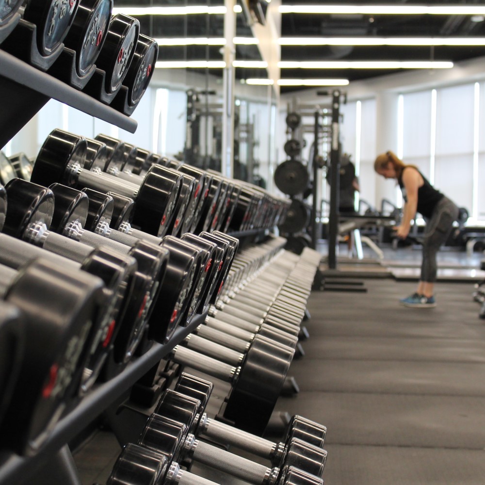 free weights and woman working out in the background using a machine